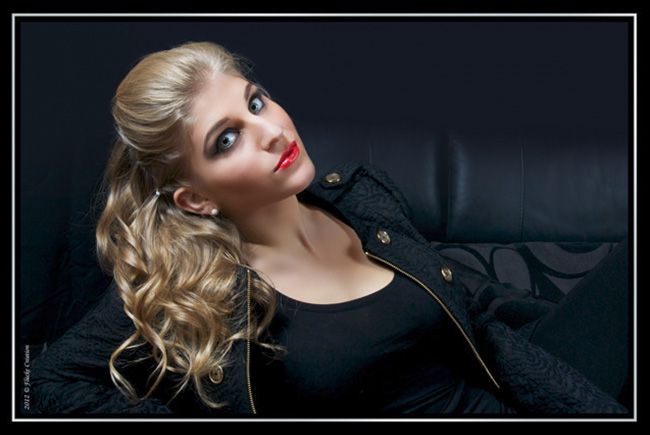 Modèle - Photographie portrait d'un modèle féminin, dont les contrastes vestimentaires et d'ambiance, sur différentes textures aux teintes noires, font ressortir son visage et sa belle chevelure dorée et ondulée